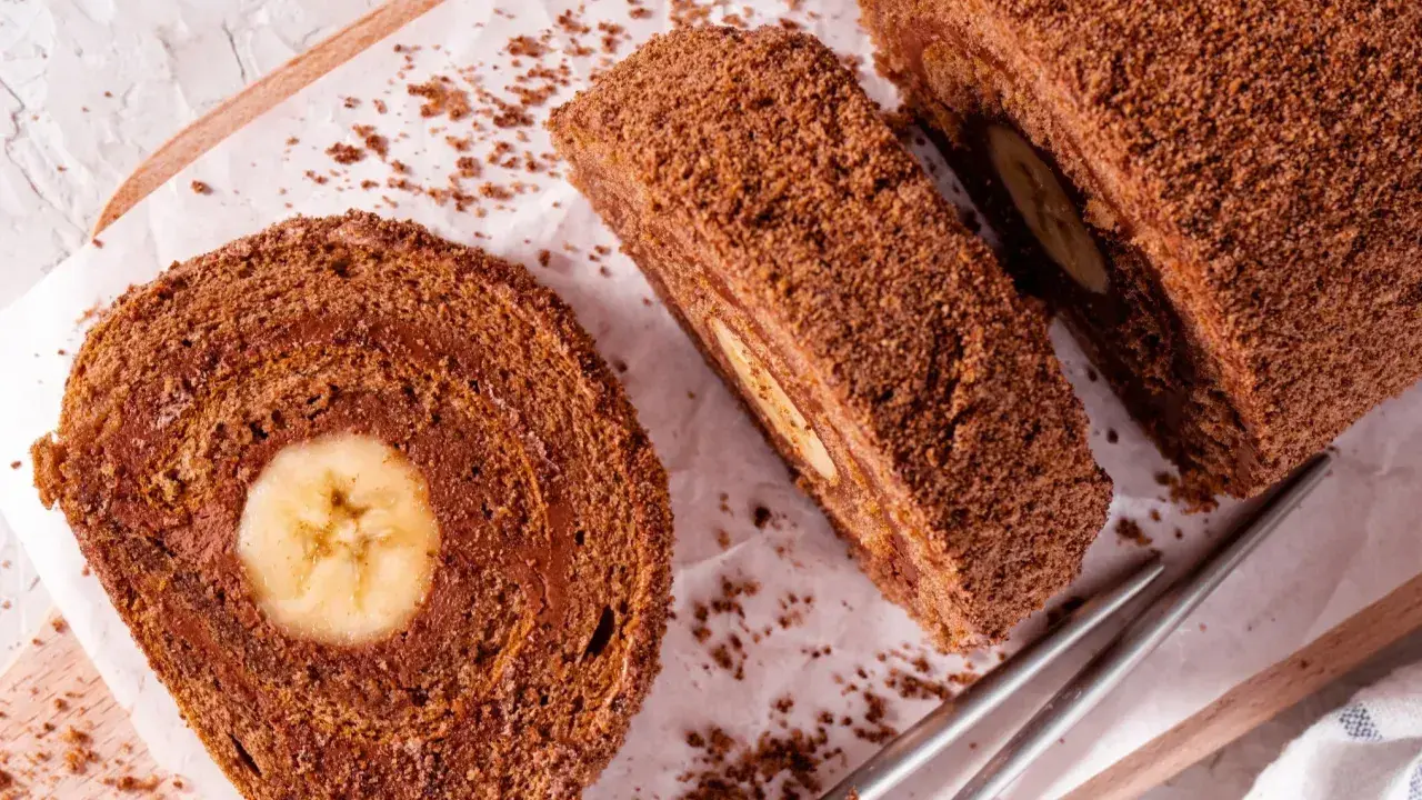 Czekoladowa, najprostsza rolada biszkoptowa z bananem w środku, posypana wiórkami. Idealna na deser.