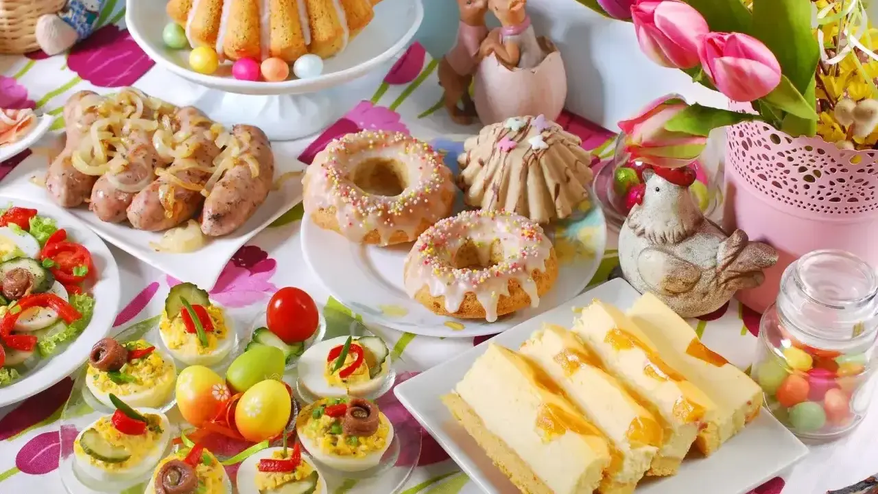 Wielkanocne potrawy: babka, kiełbaski, jajka faszerowane, sernik i słodkie przekąski.