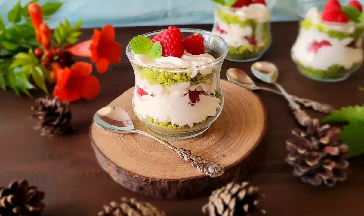Pyszne ciasto leśny mech na dużą blachę z serkiem mascarpone, podane w szklanych pucharkach, ozdobione malinami i miętą.