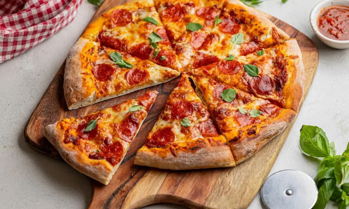Apetyczna pizza pepperoni z ciągnącym się serem i świeżą bazylią, gotowa do podania.