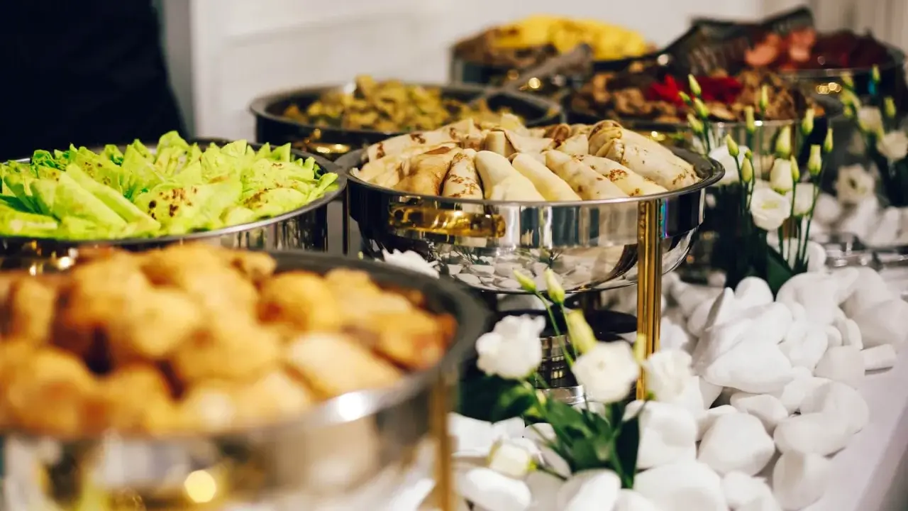 Bufet z jedzeniem: naleśniki, sałatka, smażone kąski. Zastanawiasz się, ile kosztuje catering na imprezę?