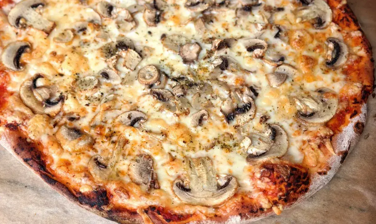 Pyszna pizza capricciosa z pieczarkami i ciągnącym się serem, idealna na szybki obiad.