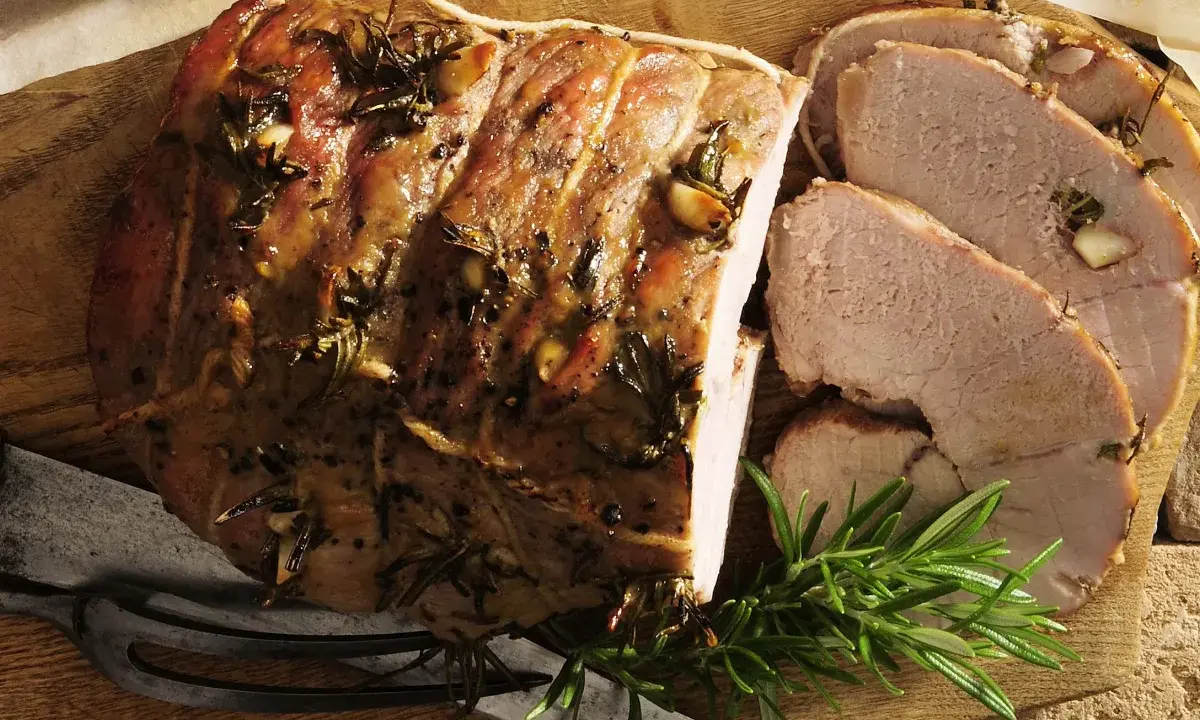 Pieczona jagnięcina co to? Soczysty, aromatyczny kawałek mięsa z rozmarynem i czosnkiem, pokrojony w plastry, gotowy do podania.