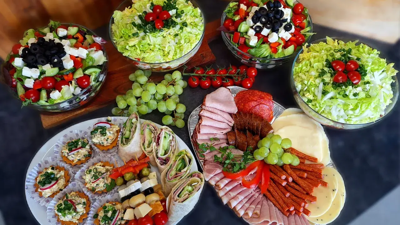 Pyszne przekąski i sałatki na talerzach. Zastanawiasz się, ile kosztuje catering do domu? To idealna opcja na imprezę!