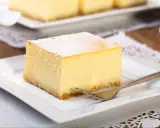 Pyszny sernik z wiaderka, idealny do pieczenia w temperaturze 170°C. Pokrojony na kwadratowe porcje, posypany cukrem pudrem, czeka na widelczyk.