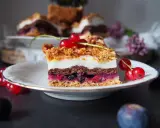 Pyszny kawałek ciasta pleśniak z dżemem porzeczkowym, ozdobiony świeżymi porzeczkami. Idealny na deser.