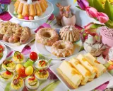 Wielkanocne potrawy: babka, kiełbaski, jajka faszerowane, sernik i słodkie przekąski.