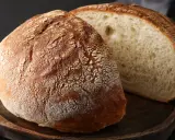 Chleb na drewnianej desce, jeden cały, drugi przekrojony. Idealny na przepis na chleb naszych babć.