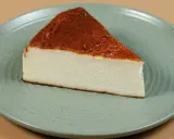 Pyszny kawałek sernika pieczonego bez spodu, z lekko przypieczoną górą, na zielonym talerzu.