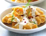 Pyszne pierogi z farszem, polane sosem i posypane koperkiem. Idealne danie, by zastanowić się, co ugotować w piątek na obiad.