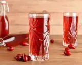 Szklanka i butelka z nalewką z derenia. Przepis na domową nalewkę z derenia jest prosty, a efekt zachwyca.