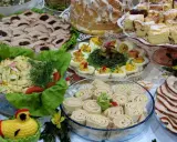Mnóstwo pyszności na stole, idealnych na to, co ugotować na święta: pieczone mięsa, sałatki, jajka faszerowane, babka i ciasta.