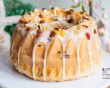 Babka wielkanocna z lukrem, rodzynkami i migdałami na białym talerzu.