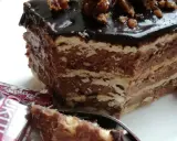 Czekoladowe ciasto bez pieczenia z wafli, idealne na przepis na ciasto kukułka bez pieczenia. Na wierzchu błyszcząca polewa i orzechy.