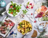 Wigilia na talerzu: pieczone ziemniaki, mięso, sałatka, ser, słodkości. Zastanawiasz się, ile kosztuje catering na wigilię?