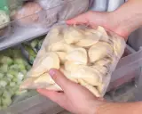 Ręce wkładają do zamrażarki worek z pierogami. To prosty sposób, jak mrozić pierogi, by cieszyć się nimi później.
