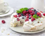 Beza Pavlova która zawsze wychodzi, udekorowana bitą śmietaną, malinami, borówkami i listkami mięty. Idealna na deser.
