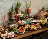 Bogaty stół z serami, owocami, ciastkami i pieczywem. Idealny na przyjęcie, zastanawiasz się, ile kosztuje catering na 15 osób?