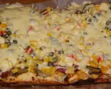 Pyszna pizza na grubym cieście z warzywami i roztopionym serem.