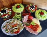 Pyszne przekąski i sałatki na talerzach. Zastanawiasz się, ile kosztuje catering do domu? To idealna opcja na imprezę!