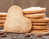 Stos cukrowych ciastek w kształcie serca i okrągłych, idealnych na prosty przepis na ciastka. Ziarna kawy i sznurek dodają uroku.