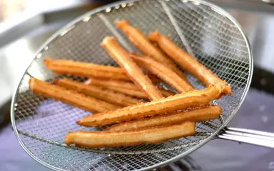 Churros co to? Złociste, chrupiące paluszki smażone na głębokim tłuszczu, wyjęte właśnie z frytownicy na metalowej łyżce cedzakowej.