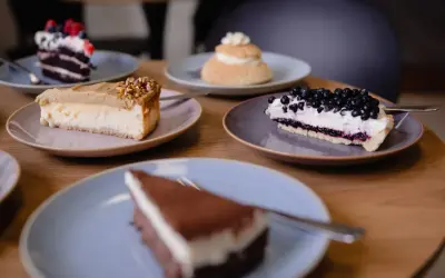 Kawa, jagody, pistacje – te składniki to klucz do najmodniejszych ciast. Na stole pięć pysznych deserów, każdy na osobnym talerzyku.