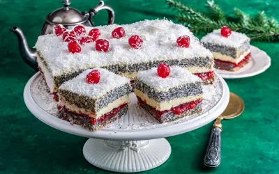 Pyszna makowa panienka z wiśniami i wiórkami kokosowymi, podana na paterze.