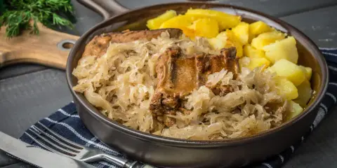 Pyszne żeberka w kapuście kiszonej, idealne do pieczenia w piekarniku. Podane z ziemniakami.