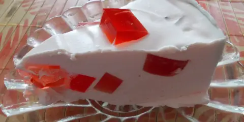 Puszysty deser z kawałkami czerwonej galaretki, przypominający ptasie mleczko z galaretki.
