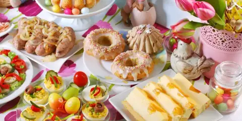 Wielkanocne potrawy: babka, kiełbaski, jajka faszerowane, sernik i słodkie przekąski.