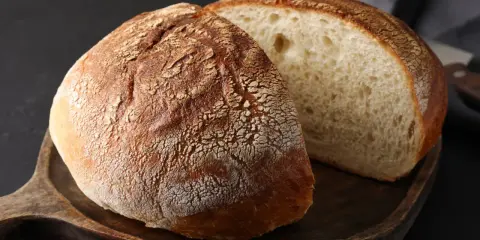 Chleb na drewnianej desce, jeden cały, drugi przekrojony. Idealny na przepis na chleb naszych babć.