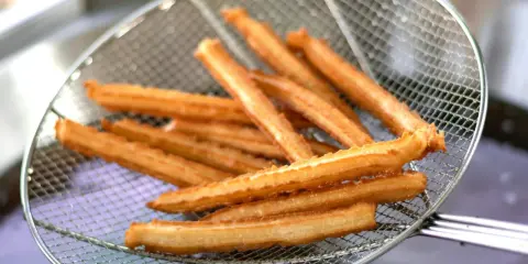 Churros co to? Złociste, chrupiące paluszki smażone na głębokim tłuszczu, wyjęte właśnie z frytownicy na metalowej łyżce cedzakowej.