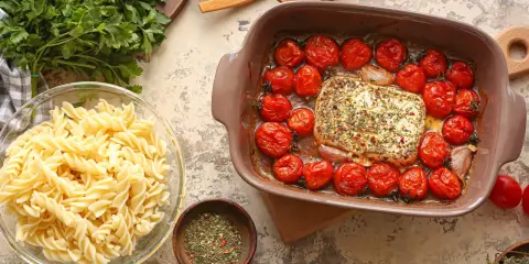 Pieczenie sera feta z pomidorkami koktajlowymi to świetny pomysł na obiad. Obok makaron fusilli i świeża natka.