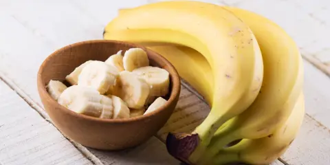 Banan wartości odżywcze: pyszne, żółte banany obok miseczki z pokrojonymi plasterkami. Idealne na zdrową przekąskę.