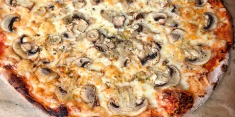 Pyszna pizza capricciosa z pieczarkami i ciągnącym się serem, idealna na szybki obiad.