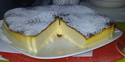 Puszysty sernik z airfryer, oprószony cukrem pudrem, z lekko przypieczoną skórką i kremowym wnętrzem.