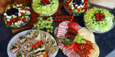 Pyszne przekąski i sałatki na talerzach. Zastanawiasz się, ile kosztuje catering do domu? To idealna opcja na imprezę!