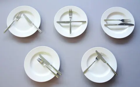 Pięć talerzy z różnie ułożonymi sztućcami, wskazujących jak jesc catering.