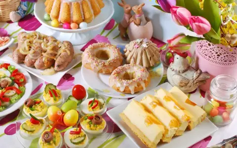 Wielkanocne potrawy: babka, kiełbaski, jajka faszerowane, sernik i słodkie przekąski.