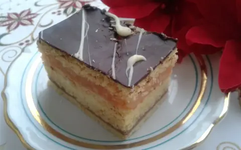 Pyszny kawałek ciasta z warstwami biszkoptu, kremu serowego i jabłek, oblany czekoladą. Idealny na przepis na ciasto delicja z serem i jabłkami.