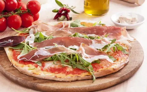 Pyszna pizza prosciutto z rukolą, pomidorkami i oliwą. Idealna na włoską ucztę.