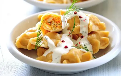 Pyszne pierogi z farszem, polane sosem i posypane koperkiem. Idealne danie, by zastanowić się, co ugotować w piątek na obiad.