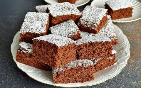 Pyszne, wilgotne ciasto czekoladowe pokrojone w kostkę, posypane cukrem pudrem. Idealne na przepis na ciasto kręcone.