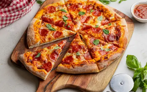 Apetyczna pizza pepperoni z ciągnącym się serem i świeżą bazylią, gotowa do podania.