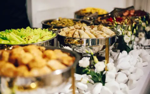 Bufet z jedzeniem: naleśniki, sałatka, smażone kąski. Zastanawiasz się, ile kosztuje catering na imprezę?