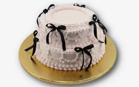 Dwupiętrowy tort w kolorze pudrowego różu, ozdobiony czarnymi wstążkami. Idealny na osiemnastkę, zastanawiasz się, ile kosztuje catering na 18?