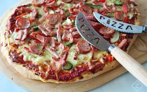 Pyszna pizza z kiełbasą i warzywami, gotowa do pokrojenia. To najlepsza pizza przepis, jaki kiedykolwiek próbowałeś!