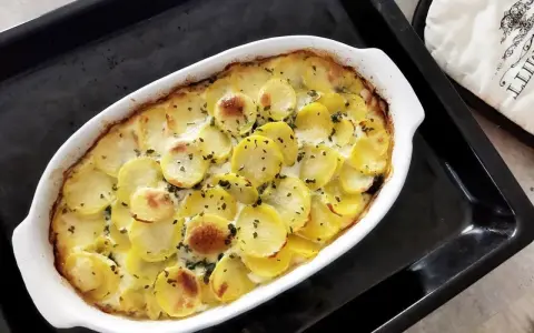 Zapiekanka ziemniaczana w kremowym sosie, posypana ziołami. Idealne danie, gdy zastanawiasz się, co na obiad tanio i smacznie.