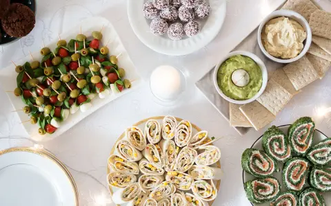 Stół z przekąskami: koreczki caprese, roladki z tortilli, łososia i szpinaku, dipy, ciasteczka.